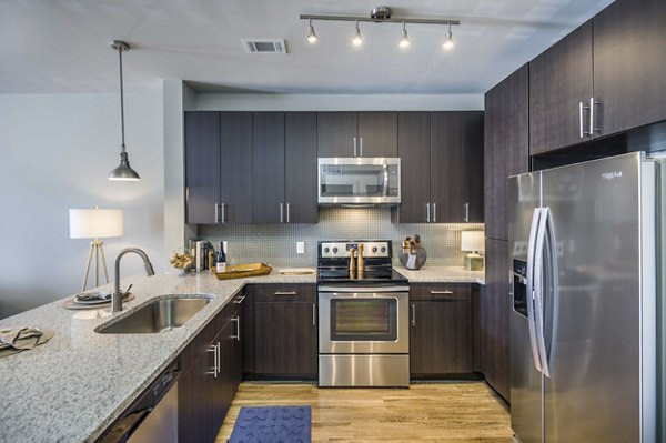 Modern kitchen with stainless steel appliances and granite countertops at Leigh House Apartments, luxury living in the heart of the city