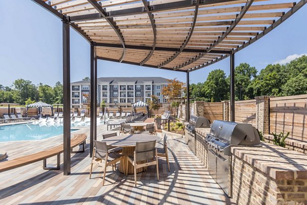 Outdoor grill area with seating at Leigh House Apartments, perfect for gatherings and dining in a vibrant community setting