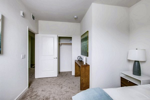 Cozy bedroom featuring modern decor and large windows at Ascent at Campus of Life Apartments in luxury Greystar community
