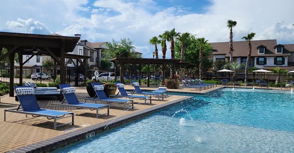 Pool with sun loungers at Grand Villas at Tuscan Lakes Apartments, offering a relaxing outdoor oasis for residents