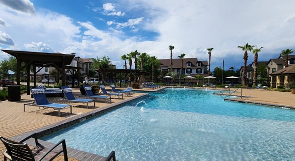 Serene poolside retreat at Grand Villas at Tuscan Lakes Apartments, featuring lounge chairs and lush landscaping for relaxation