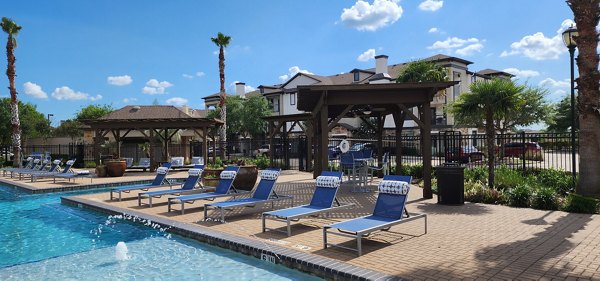 Sunlit outdoor pool at Grand Villas at Tuscan Lakes Apartments with palm trees and lounge chairs, perfect for relaxation and leisure activities