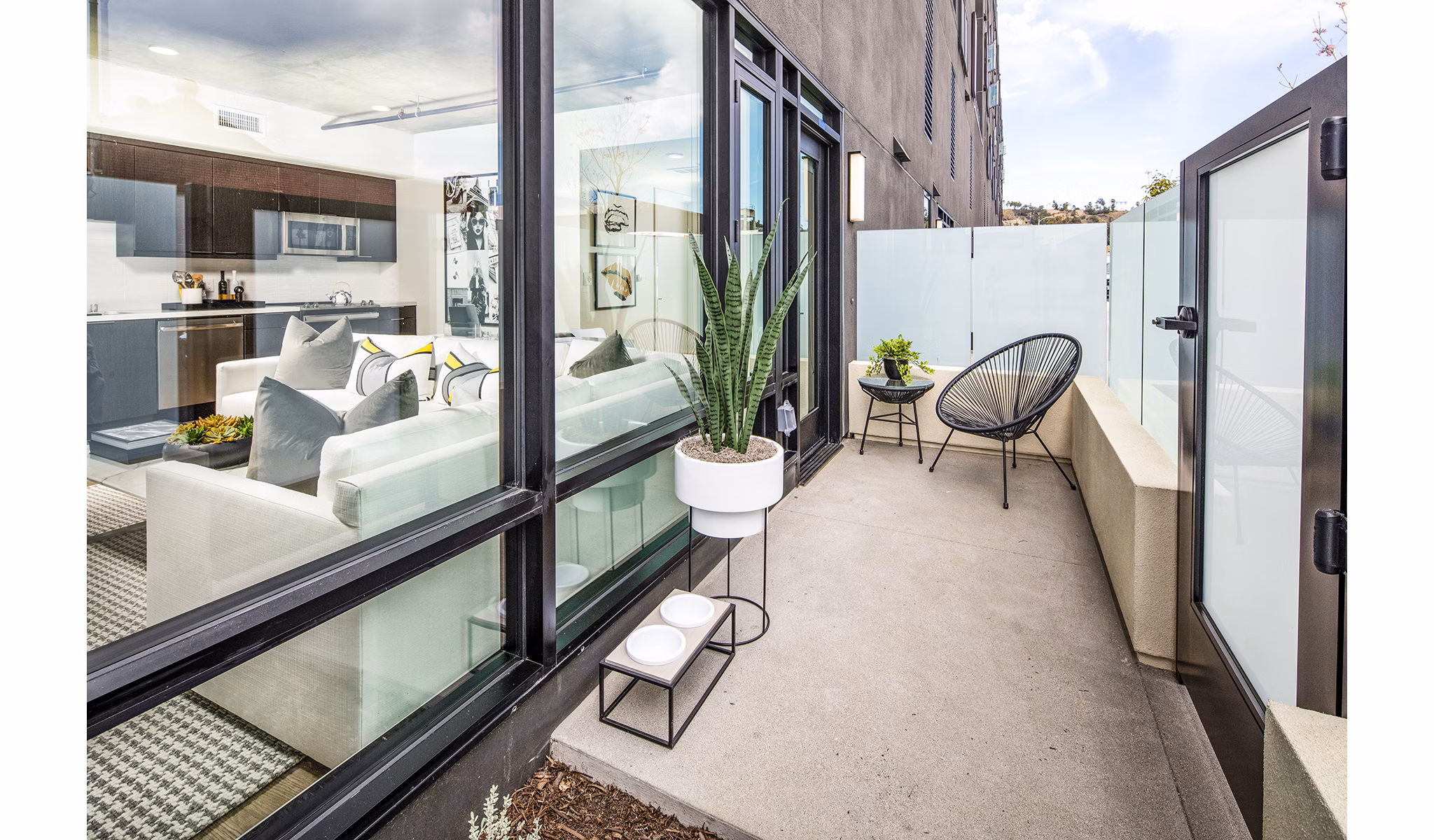 Patio with modern furniture and potted plants at Llewellyn Apartments, offering a luxurious outdoor living space in a high-rise community