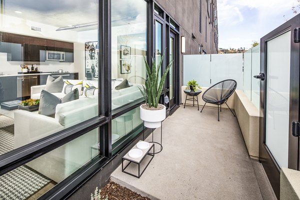 Patio with modern furniture and potted plants at Llewellyn Apartments, offering a luxurious outdoor living space in a high-rise community