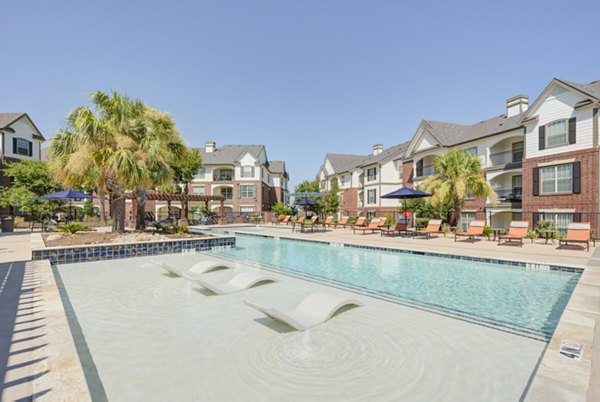 Sunlit outdoor pool with lounging area at Lone Oak Apartments, perfect for relaxation and leisure activities
