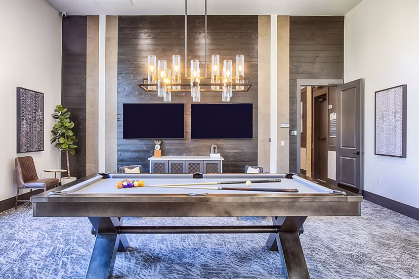 Game room with pool table and lounge seating at Rockrimmon Apartments clubhouse, ideal for socializing in a luxury setting