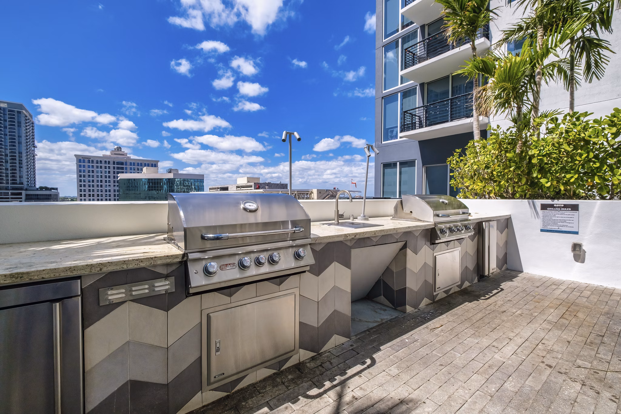 Grill station in landscaped courtyard at NOVO Las Olas Apartments, perfect for outdoor cooking and socializing in a luxury setting