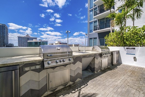 Grill station in landscaped courtyard at NOVO Las Olas Apartments, perfect for outdoor cooking and socializing in a luxury setting