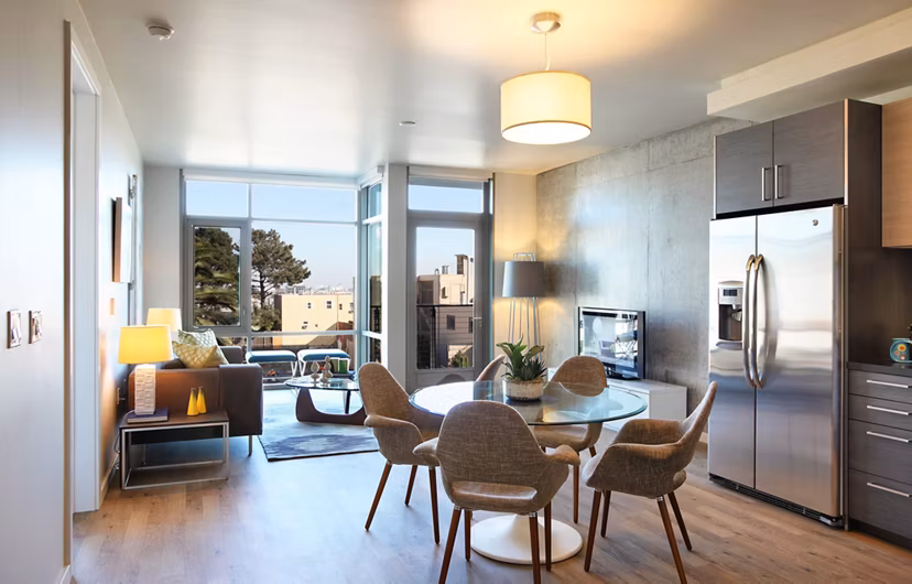 Modern living and dining area with large windows, round table, and sofa in luxury apartment