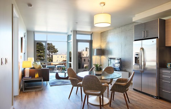 Modern living and dining area with large windows, round table, and sofa in luxury apartment