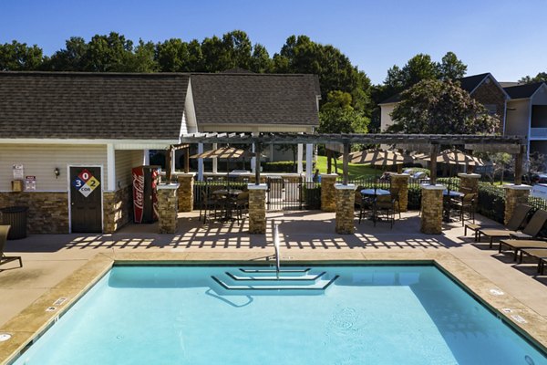 Resort-style swimming pool at Avana Avebury Apartments, featuring lounge chairs and lush landscaping