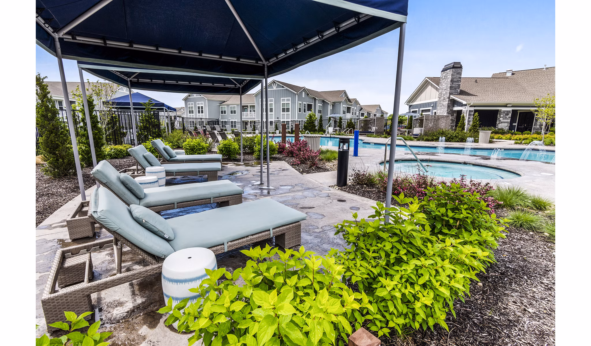 Poolside patio with lounge chairs at The Landing at Tiffany Springs Apartments, offering luxury outdoor relaxation space