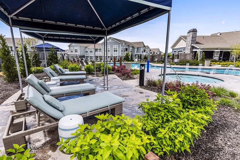 Poolside patio with lounge chairs at The Landing at Tiffany Springs Apartments, offering luxury outdoor relaxation space