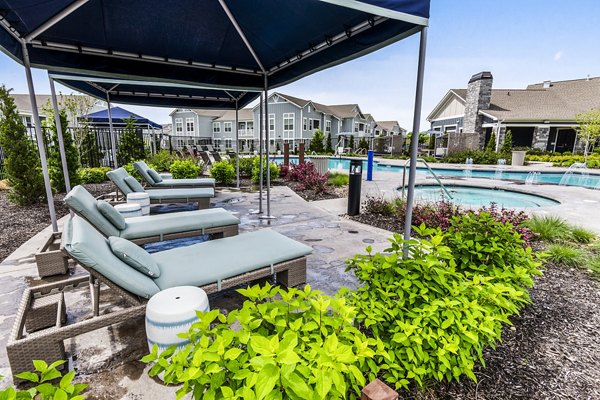 Poolside patio with lounge chairs at The Landing at Tiffany Springs Apartments, offering luxury outdoor relaxation space