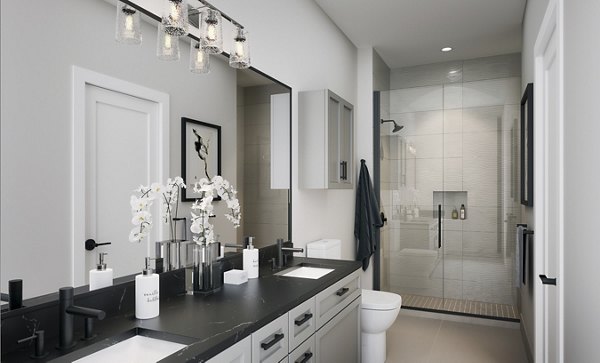Modern bathroom featuring a black countertop, large mirror, and walk-in shower with decorative lighting
