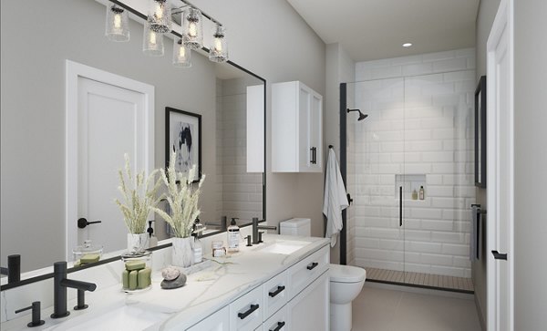 Modern bathroom with large mirror and dual sinks featuring glass shower at luxury apartments