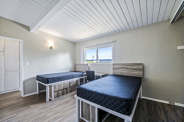 Spacious bedroom with modern decor at Breakpointe Coronado Apartments, featuring a large window and stylish furnishings