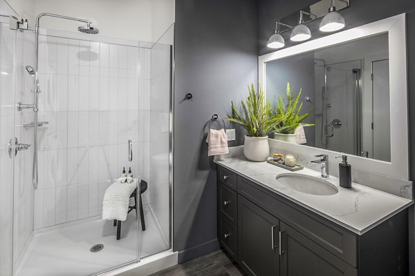 Modern bathroom with sleek fixtures and large mirror at Mercato Grove Apartments