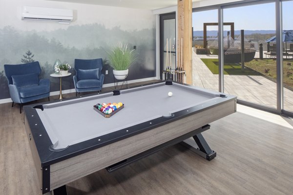 Game room with billiards table and flat-screen TVs at Aria Apartments for entertainment and social gatherings