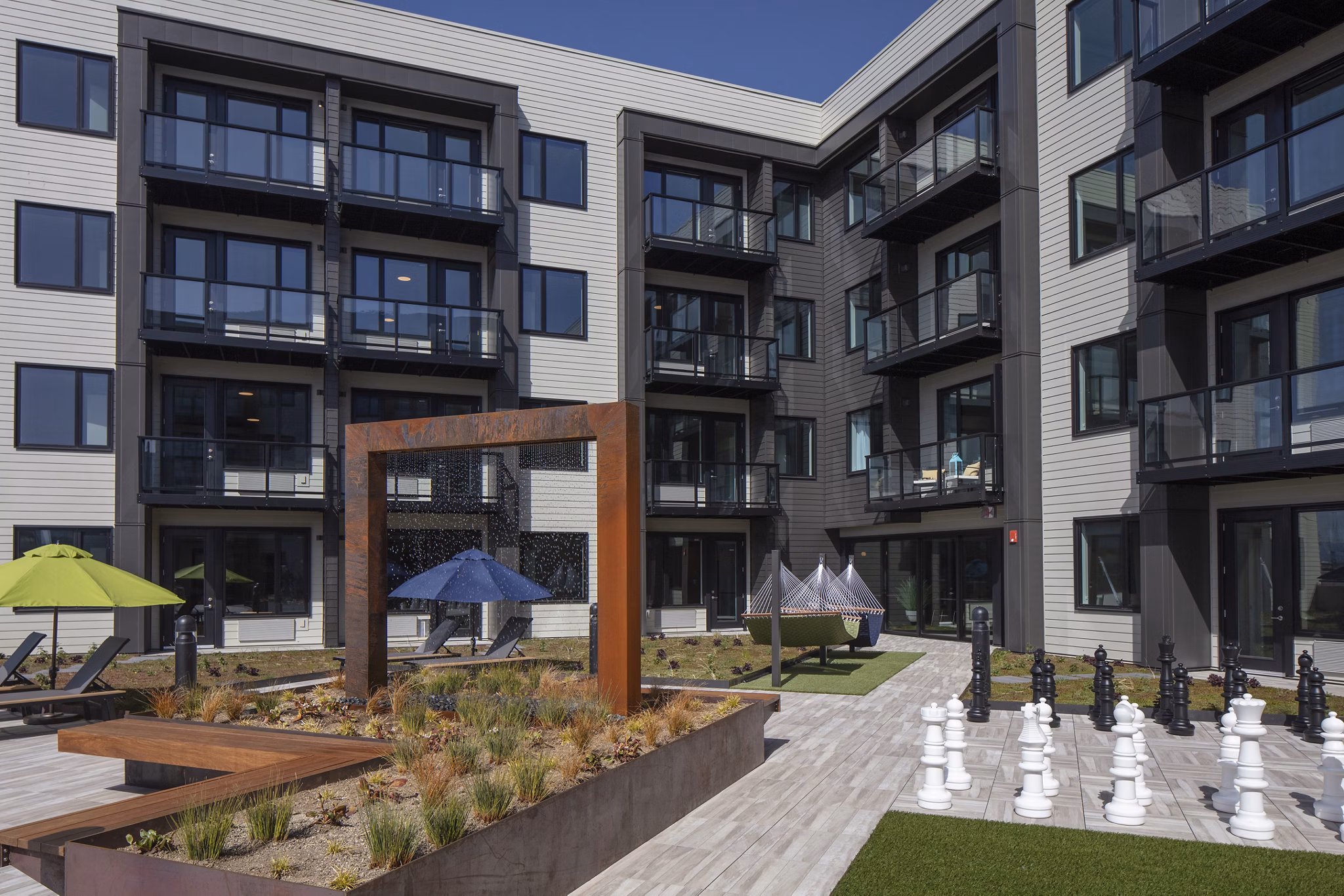 Chic courtyard with manicured greenery at Aria Apartments, offering luxurious outdoor space for residents to relax and socialize