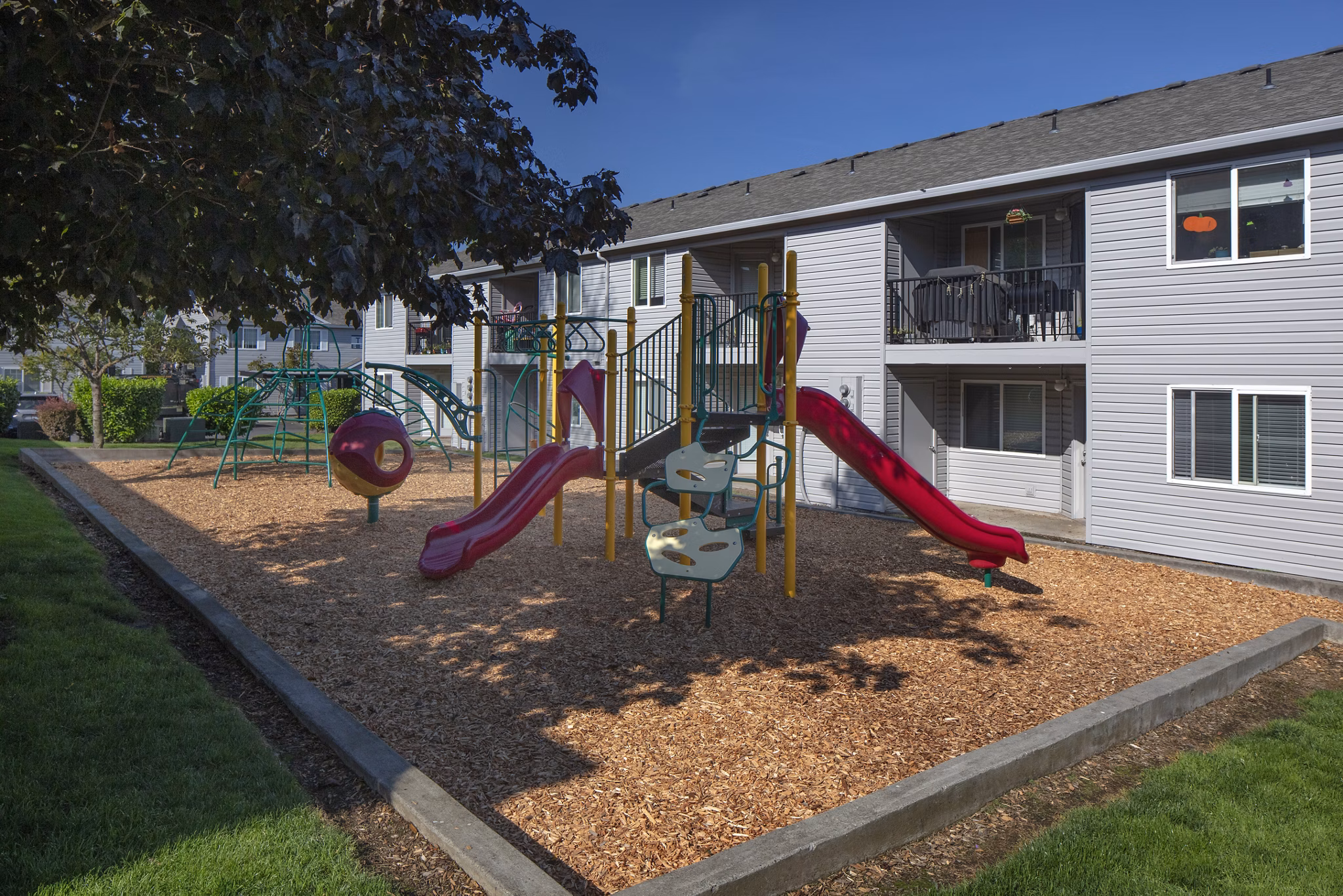 Playground with colorful slides and climbing structures at Avana Evergreen Apartments for family-friendly outdoor fun