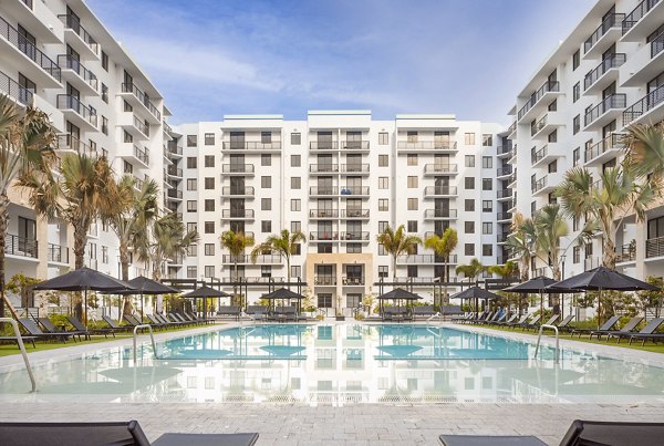 Relaxing pool area at Biscayne 112 Apartments featuring modern lounge chairs and lush landscaping