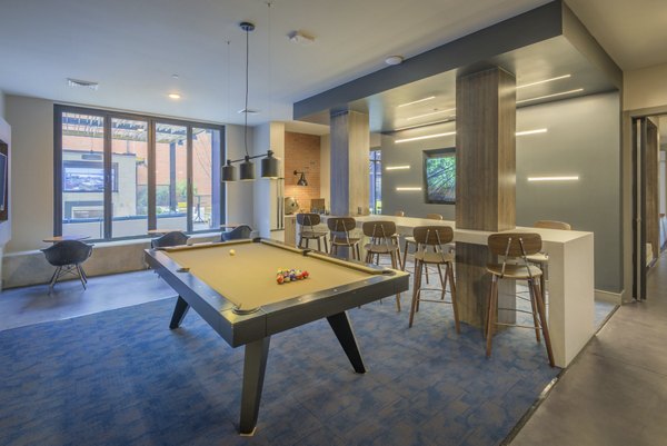 Game room with pool table and lounge seating at The Dillon Apartments, offering residents leisure and entertainment options in a luxury setting