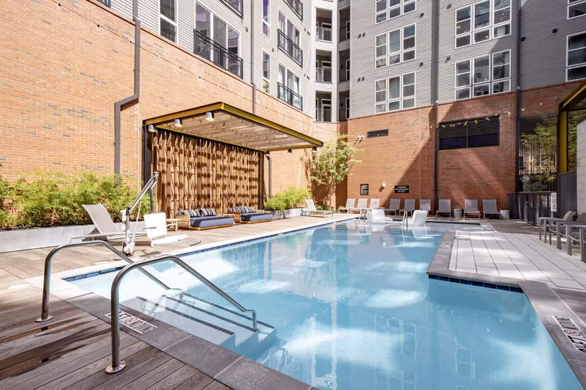 Inviting outdoor pool with lounge seating at The Dillon Apartments, offering luxury relaxation in a vibrant community setting