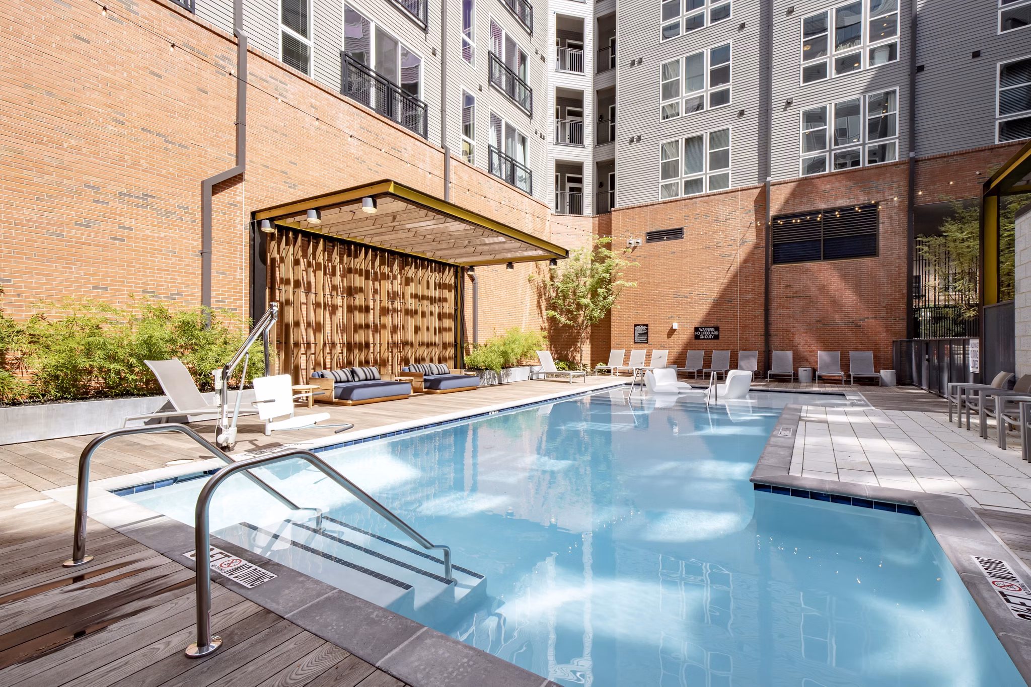 Inviting outdoor pool with lounge seating at The Dillon Apartments, offering luxury relaxation in a vibrant community setting