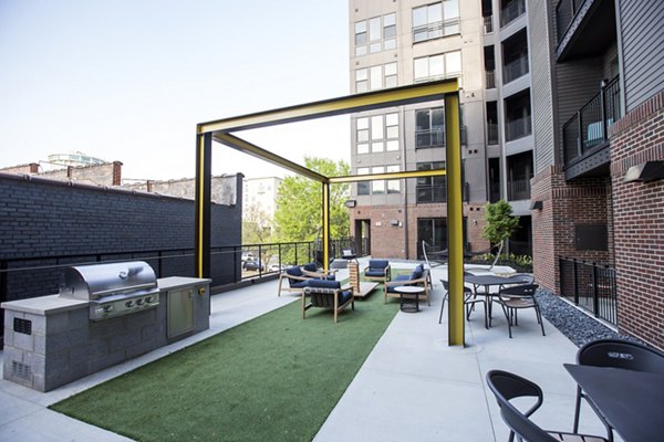 Outdoor patio area with seating, grill, and pergola structure at luxury apartments