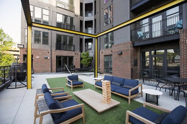 Outdoor seating area with blue cushioned chairs and Jenga game at luxury apartments