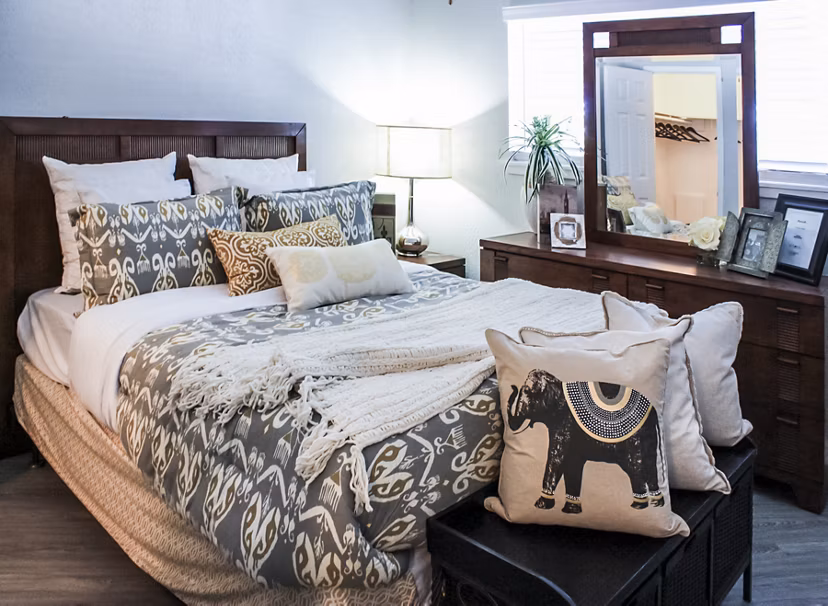 Elegant bedroom with modern decor at 3 Corners West Apartments, featuring cozy bedding and ample natural light