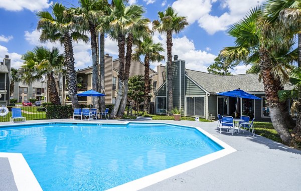 Resort-style pool with palm trees at Hammerly Oaks Apartments, offering luxury relaxation in a serene setting