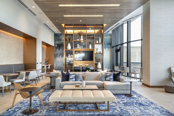 Modern clubhouse featuring lounge chairs and large TV at Eastline Residences Apartments