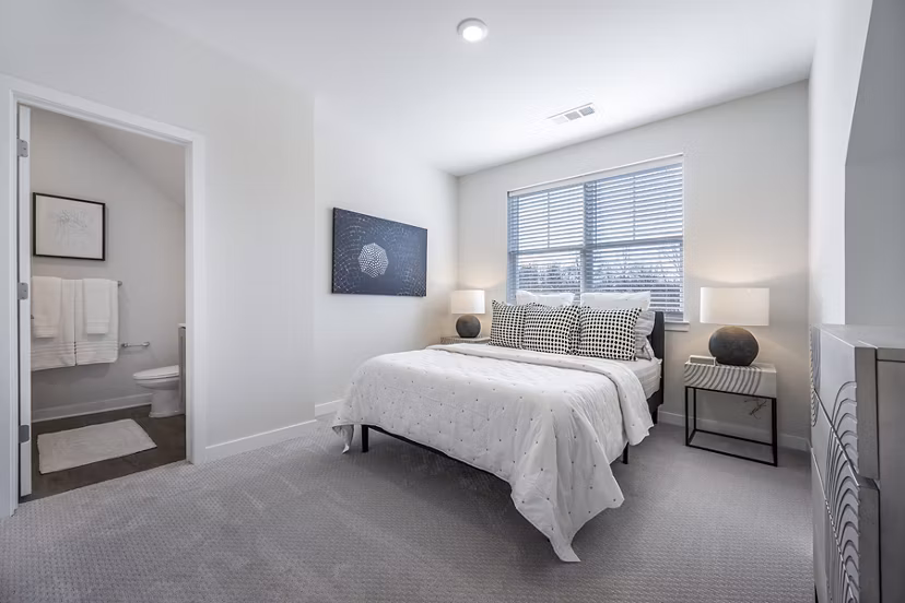 Bedroom featuring modern decor and ample natural light at Woodside Trumbull Apartments