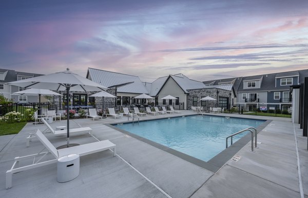 Luxurious poolside area at Woodside Trumbull Apartments with loungers and lush greenery, offering a relaxing retreat for residents