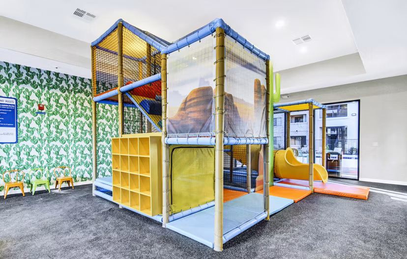 Indoor playground featuring vibrant play structures at HUE97 Apartments, a Greystar luxury offering