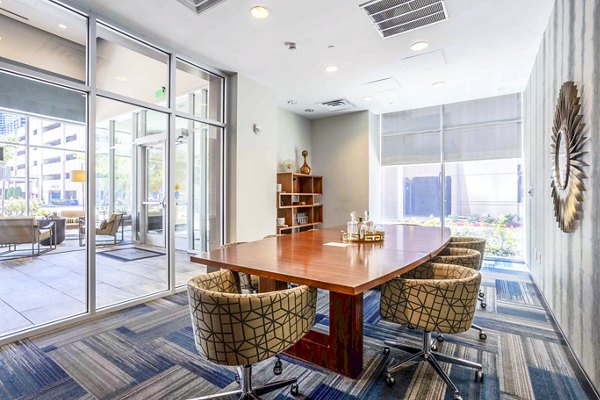 Spacious meeting room with modern seating and projection screen at SoDo on Main North Apartments clubhouse