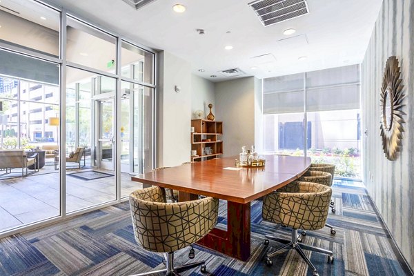 Spacious meeting room with modern seating and projection screen at SoDo on Main North Apartments clubhouse