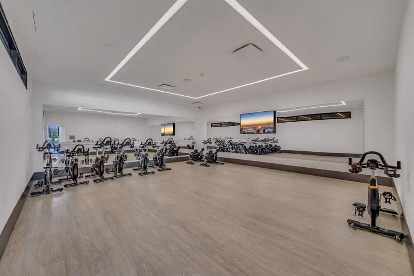 Yoga and spin studio with mirrored walls and modern equipment at Kurve Apartments, a premium living community promoting wellness