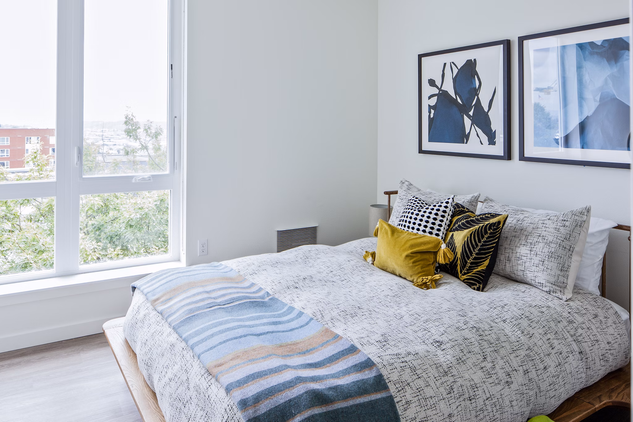 Cozy bedroom with modern decor and large window at Cypress Apartments, a Greystar community in luxury living