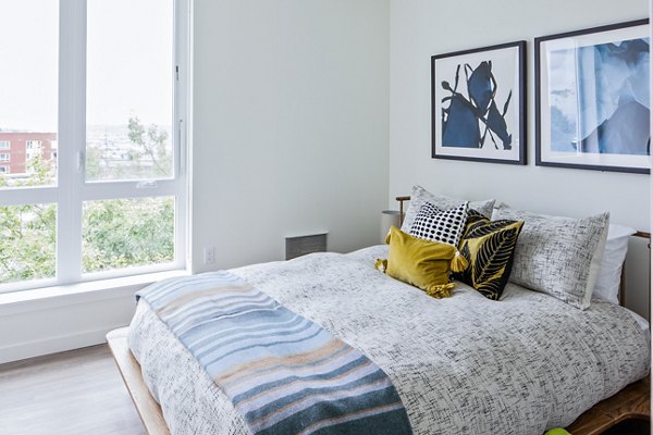 Cozy bedroom with modern decor and large window at Cypress Apartments, a Greystar community in luxury living