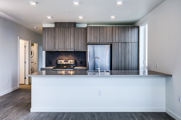 Modern kitchen with stainless steel appliances and granite countertops in Cypress Apartments