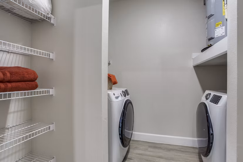 Laundry room with modern appliances and ample folding space at Quest Apartments