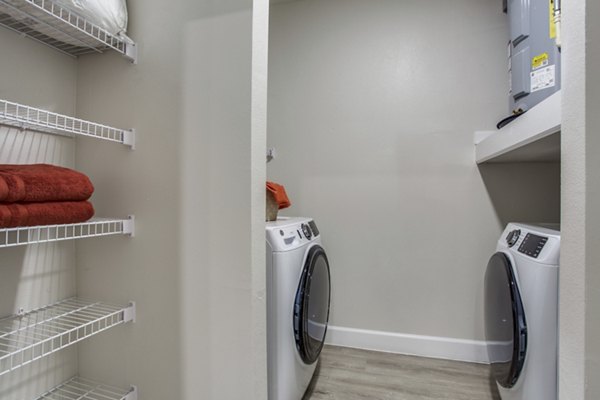 Laundry room with modern appliances and ample folding space at Quest Apartments