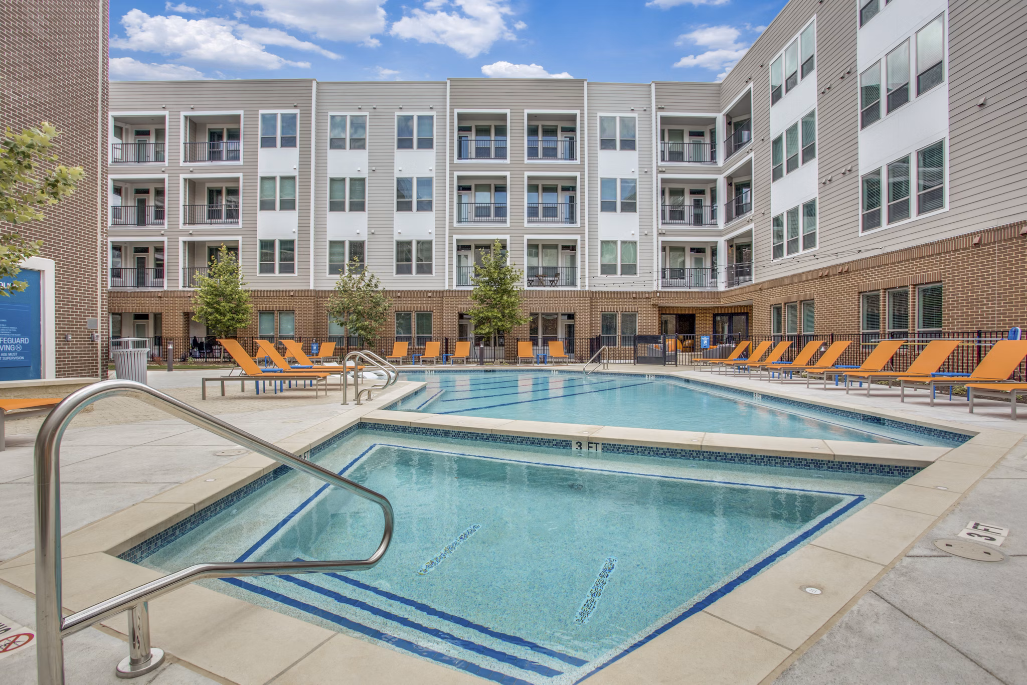 Panoramic pool views at Quest Apartments' luxury recreation area with lounge seating nearby