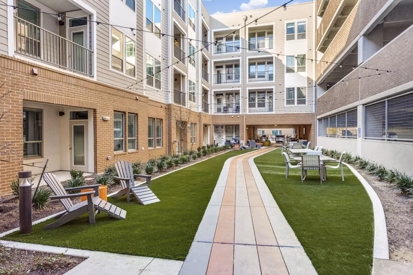 Quest Apartments: Serene courtyard with lush landscaping and seating in luxury Greystar apartment community