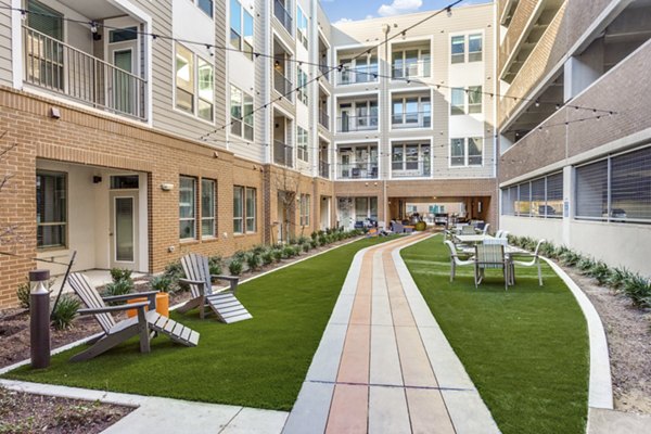 Quest Apartments: Serene courtyard with lush landscaping and seating in luxury Greystar apartment community