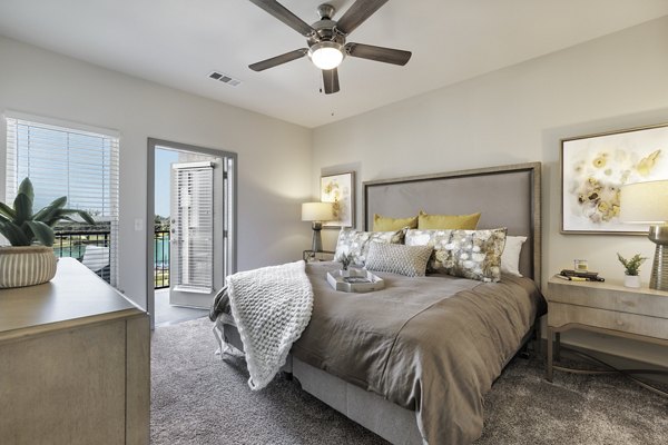 Cozy bedroom with neutral tones and large windows in Arista Riverstone Apartments