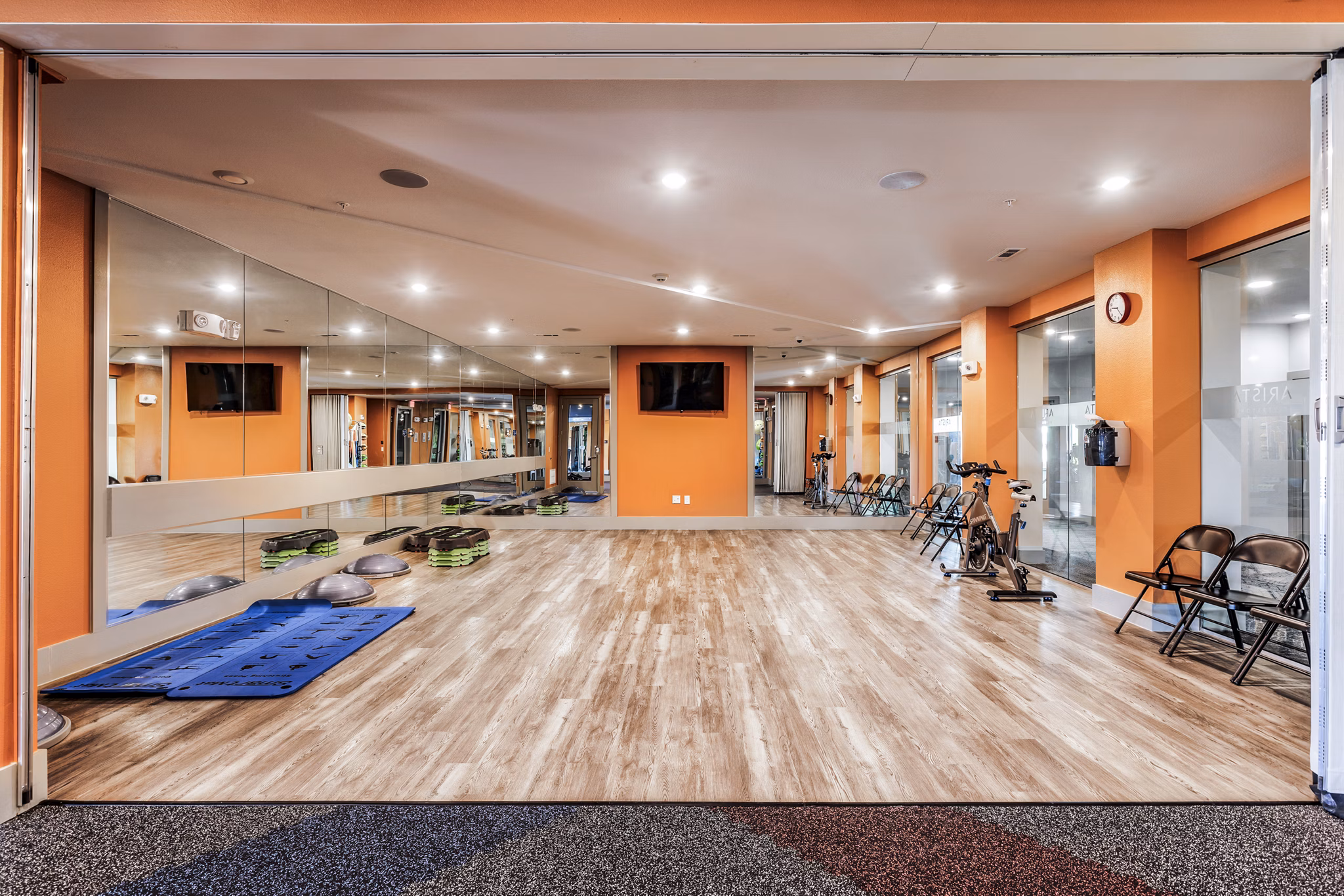Yoga studio with wood floors and large mirrors at Arista Riverstone Apartments Luxury fitness spaces enhancing wellness-focused lifestyles